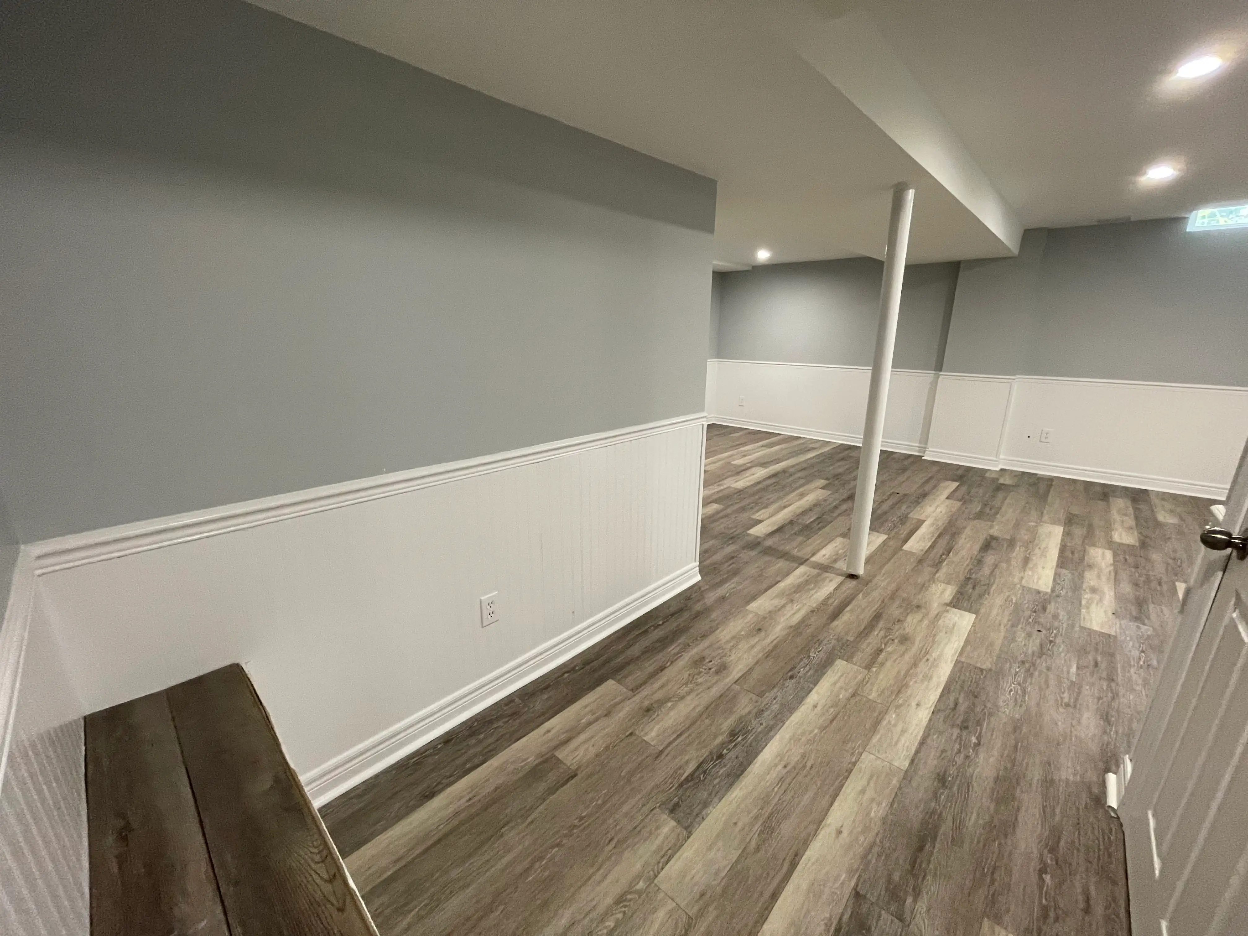 Finished legal basement suite by HMH Construction with wainscoting and luxury vinyl plank flooring