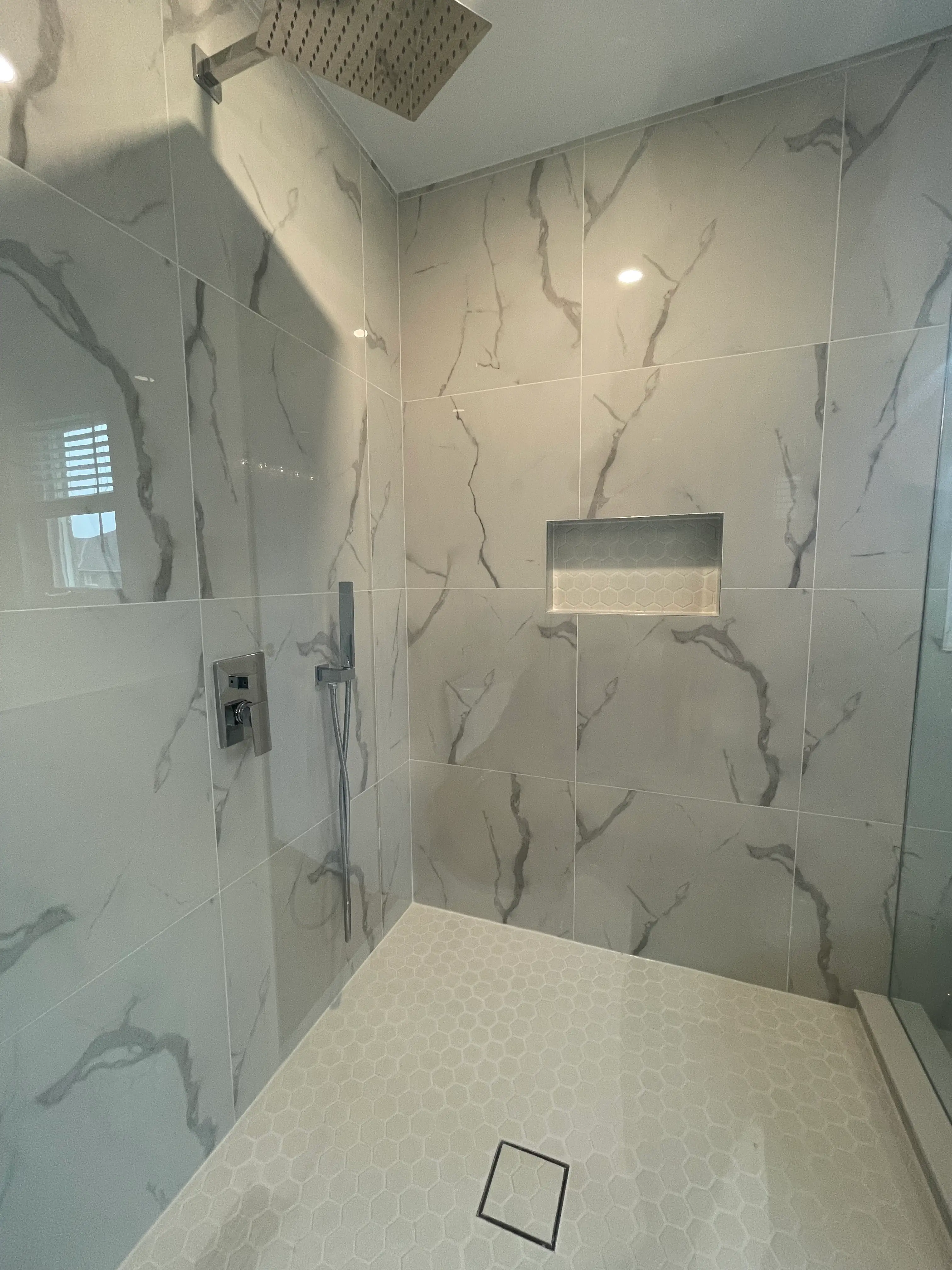 Custom walk-in shower with porcelain marble-look tile and rain head