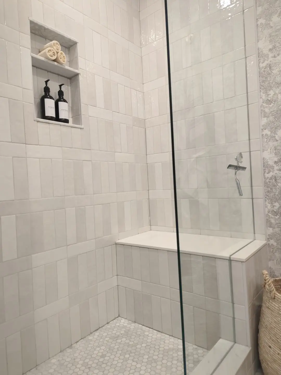 Finished — Completed tiled walk-in shower with bench seat, glass partition, and built-in niche.